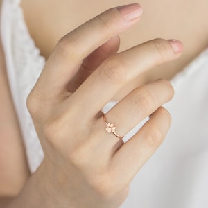 A high-quality band ring with a tiny paw print with a distinct separation between the pads in rose gold worn by a model.