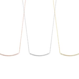 All three color options of the solid gold necklace with a thin cable chain and a curved diamond bar. Rose, white and yellow gold, every option displayed right next to each other on a white background.