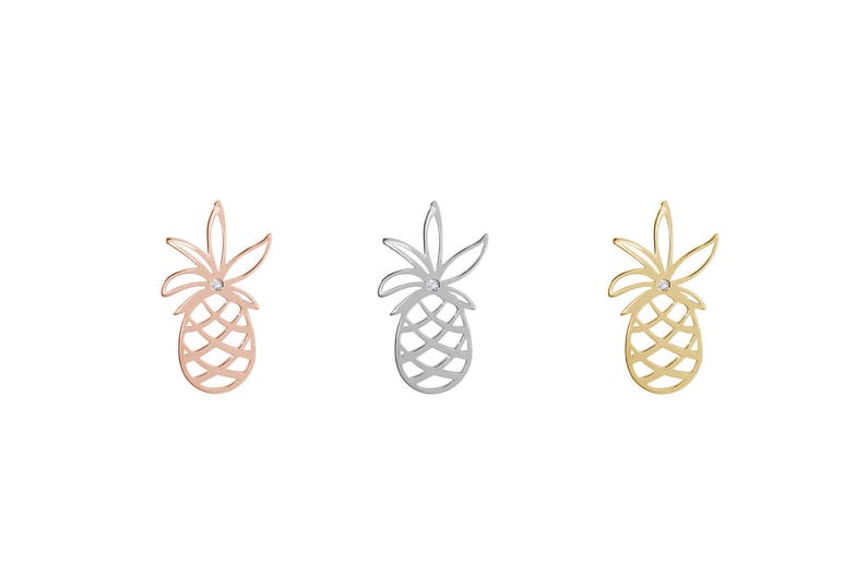 All three color options of the solid gold delicate pineapple stud earring with a white natural diamond in the center of the leaves. Rose, white and yellow gold, every option displayed right next to each other on a white background.