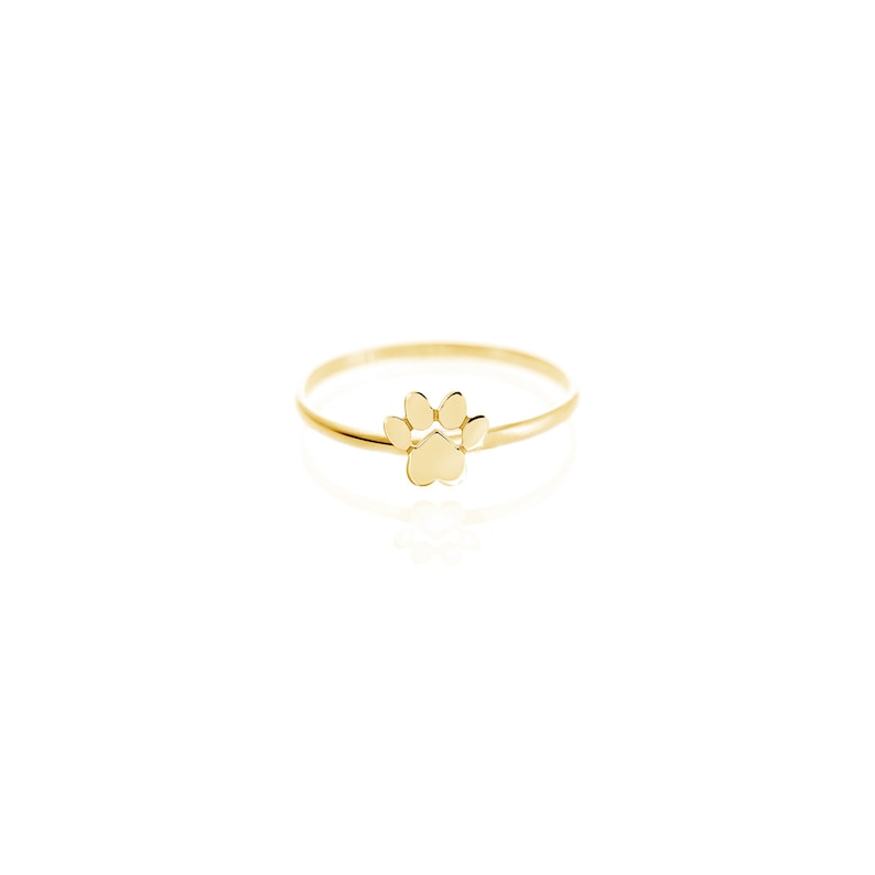 Puede incluir: Un anillo de oro con una huella de pata. El anillo es simple y delicado, con un peque&ntilde;o dise&ntilde;o de huella de pata.