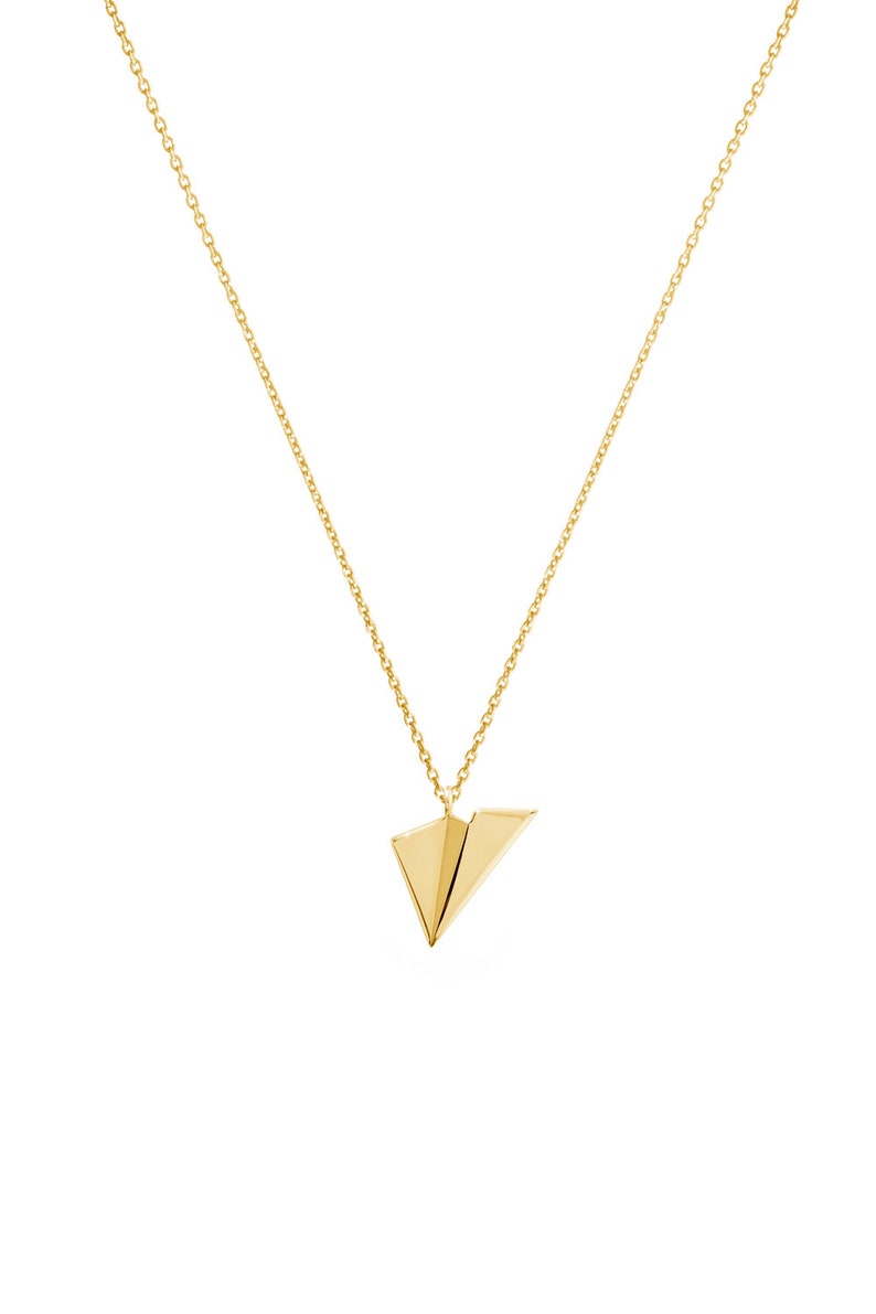 Op de afbeelding: Een gouden ketting met een klein gouden papieren vliegtuigje als hanger.