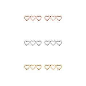 All three color options of the solid gold three-heart outline stud earrings. Rose, white and yellow gold, every option displayed right next to each other on a white background.