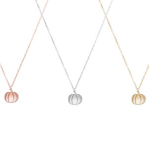 All three color options of the solid gold pendant necklace with a pumpkin charm with engraved details. Rose, white and yellow gold, every option displayed right next to each other on a white background.