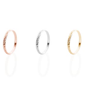 All three color options of the solid gold ring with a hammered surface on the outer part and a pished on the inside. Rose, white and yellow gold, every option displayed right next to each other on a white background.