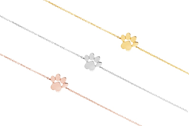 All three color options of the paw print bracelet with an adjustable chain in yellow, white and rose gold.