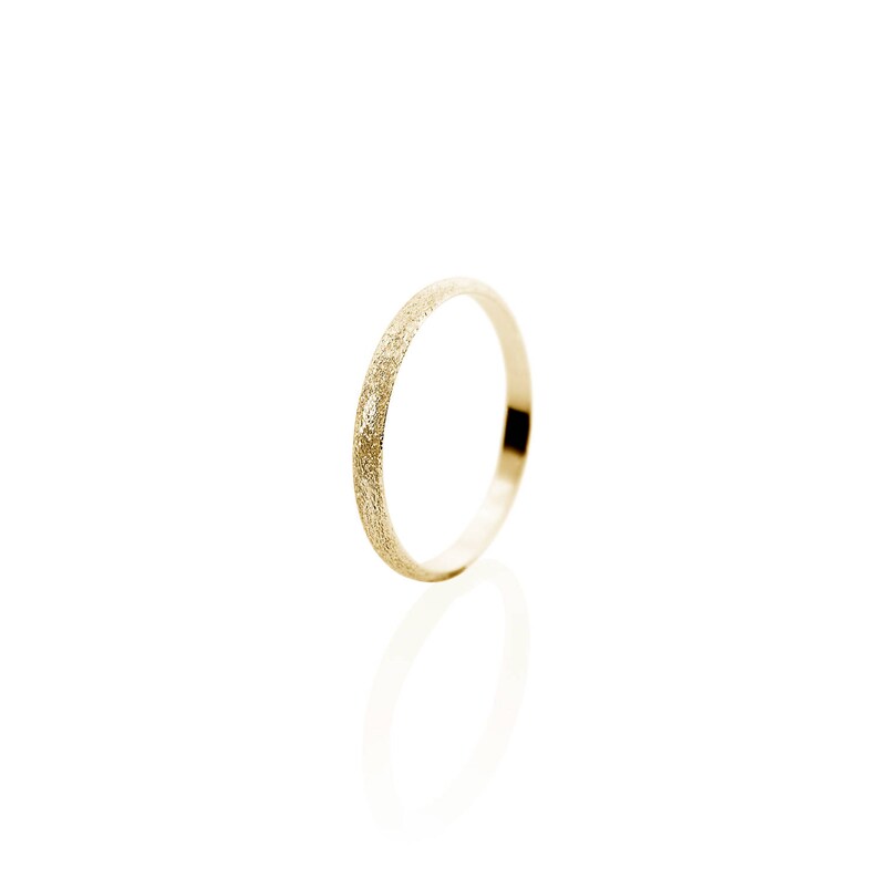 May include: A thin gold band ring with a textured finish.