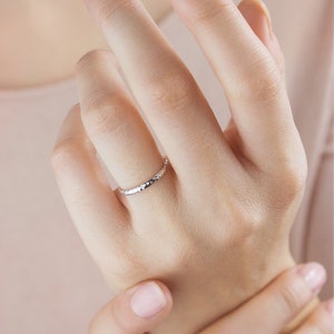 A yellow gold ring with a hammered surface on the outer part and a pished on the inside is laid beautifully shown worn by a model.