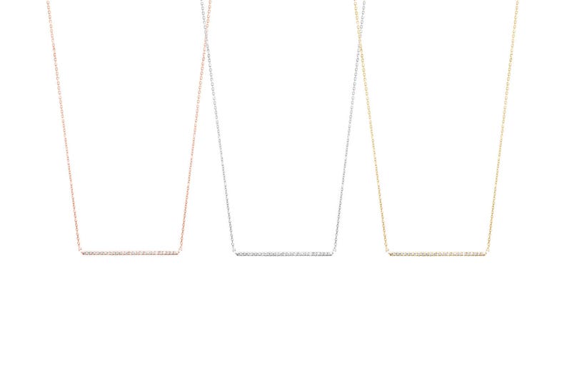 All three color options of the solid gold necklace with a thin cable chain and a diamond bar. Rose, white and yellow gold, every option displayed right next to each other on a white background.