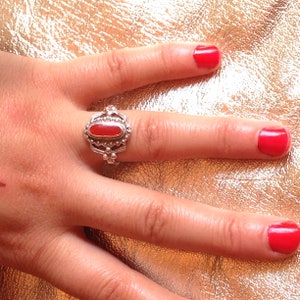 Peut inclure: Une bague en argent avec une pierre ovale rouge sertie dans un motif de filigrane d&eacute;taill&eacute;.