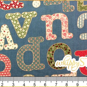 May include: A blue fabric with a patchwork design featuring colorful letters. The letters are outlined in white and have a vintage style. The fabric is marked with "whippy STIX" in gold lettering.