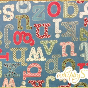 May include: A blue fabric with a pattern of colorful letters in different fonts and sizes. The letters are made of patchwork fabric with various patterns. The fabric is labeled "whippy STIX".