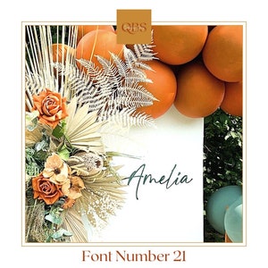 Puede incluir: Un cartel blanco con el nombre Amelia escrito en letra cursiva. El cartel está decorado con hojas de palma secas, flores y una guirnalda de globos naranjas.