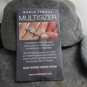 May include: A black and white card with the text "WORLD FAMOUS MULTISIZER" and instructions on how to use a ring sizer. The card shows a hand wearing a silver ring sizer.
