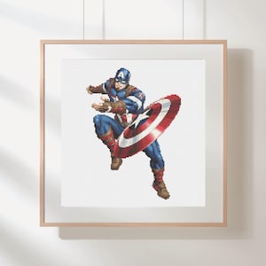 以下が含まれることがあります： キャプテン・アメリカが象徴的な盾を持ち、ダイナミックなポーズをとっている額入りのアートワーク。このアートワークは、キャラクターのクラシックな青、赤、白のコスチュームを表現しています。シールドは赤、白、青で、中央に星があります。