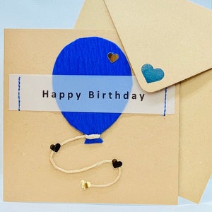 Globo azul de feliz cumpleaños sobre tarjeta marrón