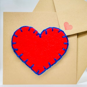 Groot rood hart met blauwe stiksels op bruine kaart
