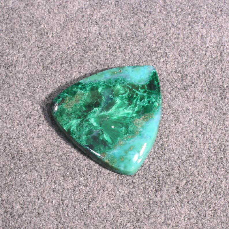 Puede incluir: Un cabuj&oacute;n de piedra preciosa verde y azul con forma triangular. La piedra tiene un patr&oacute;n &uacute;nico de remolinos y vetas.