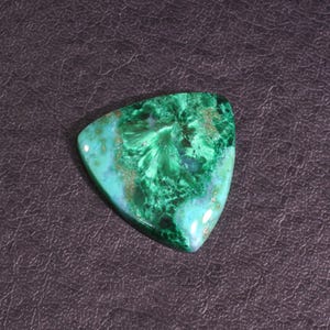 Puede incluir: Una piedra preciosa cabuj&oacute;n triangular verde y azul con un patr&oacute;n de remolino. La piedra preciosa est&aacute; engastada en un engaste plateado.