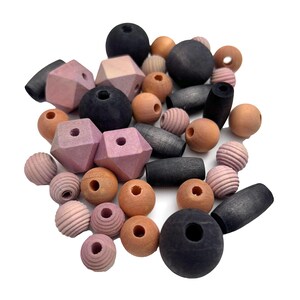 May include: A collection of wooden beads in various shapes and colors. The assortment includes round, geometric, and cylindrical beads in shades of black, pink, and natural wood tones. Some beads have a textured, ridged surface.