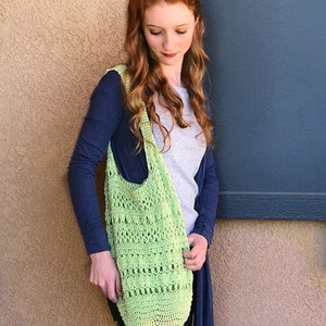Puede incluir: Una mujer con un c&aacute;rdigan azul y una camisa blanca sostiene una bolsa de mano de crochet verde claro.