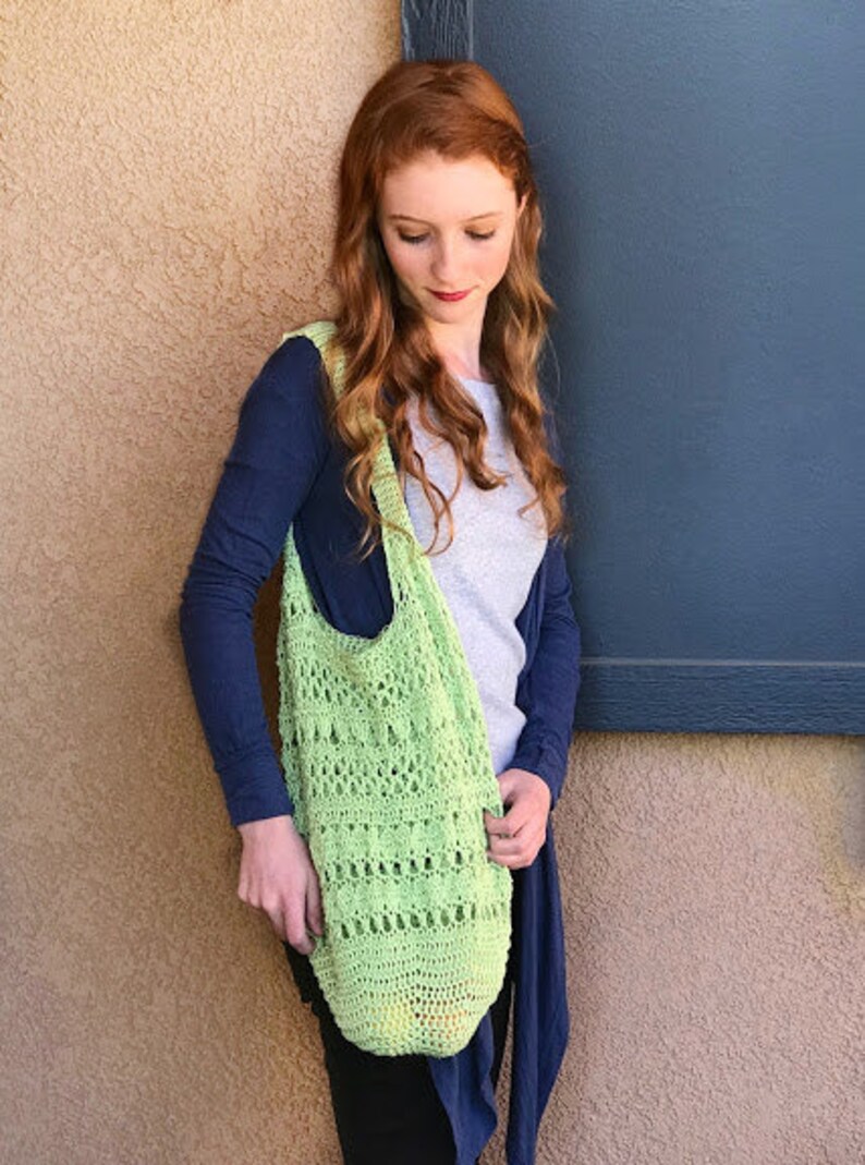 Puede incluir: Una mujer con un c&aacute;rdigan azul y una camisa blanca sostiene una bolsa de mano de crochet verde claro.