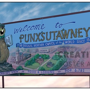 Può includere: Un cartello blu e bianco con il testo "Benvenuti a Punxsutawney" e un marmotta dei cartoni animati che tiene un libro e un ombrello. Il cartello include anche il testo "The Original Weather Capitol of the World Since 1887", "Gobbler's Knob", "Food & Lodging", e "Pop. 6,782".