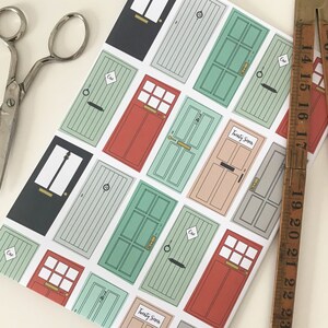 May include: White wrapping paper with a repeating pattern of colorful doors. The doors have different colors, including red, green, and blue. Some doors have the number "One" written on them. The text "Twenty Seven" appears on two of the doors.
