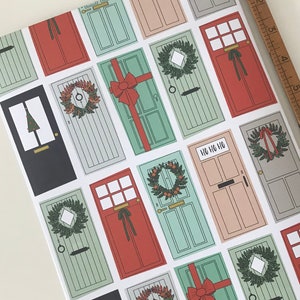 K&ouml;nnte beinhalten: Ein festliches Geschenkpapier mit einem sich wiederholenden Muster aus roten, gr&uuml;nen und wei&szlig;en T&uuml;ren mit Stechpalmenkr&auml;nzen und dem Text "Ho Ho Ho".