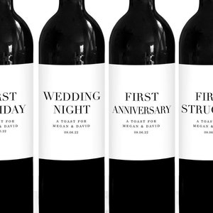 May include: Six wine bottles with silver tops and black bodies. Each bottle has a white label with black text. The labels read "First Holiday," "Wedding Night," "First Anniversary," "First Struggle," "First Dinner Party," and "First Big Purchase."