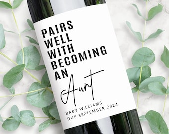 May include: A white wine bottle label with black text that reads "Pairs well with becoming an Aunt". The text "Baby Williams Due September 2024" is also on the label.