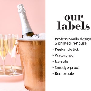 Peut inclure: Un seau &agrave; champagne en cuivre contenant une bouteille de champagne et de la glace. Le seau est pos&eacute; sur une surface rose avec des fl&ucirc;tes &agrave; champagne en arri&egrave;re-plan. Le texte "our labels" est en gras noir avec une liste de caract&eacute;ristiques&nbsp;: con&ccedil;u et imprim&eacute; professionnellement en interne, autocollant, imperm&eacute;able, r&eacute;sistant &agrave; la glace, anti-taches et amovible.