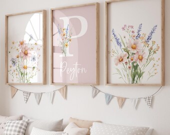 May include: Three framed floral art prints with wooden frames hang above a storage bench. One print features a large letter "P" and the name "Peyton" in script. The other two prints display watercolor flower arrangements in soft colors.