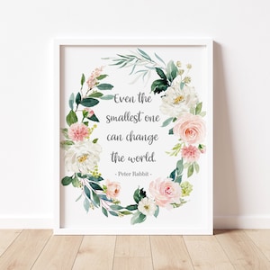 Puede incluir: Una impresión enmarcada en blanco con una corona floral de acuarela en tonos de rosa, blanco y verde. La cita "Incluso el más pequeño puede cambiar el mundo. - Peter Rabbit" está escrita en texto gris dentro de la corona.