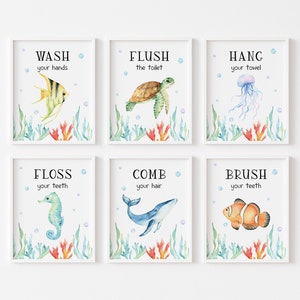 Puede incluir: Seis ilustraciones de acuarela de criaturas marinas con instrucciones relacionadas con el baño. Las ilustraciones incluyen un pez, una tortuga, una medusa, un caballito de mar, una ballena y un pez payaso. El texto dice: "Lávate las manos", "Tira de la cadena", "Cuelga tu toalla", "Usa hilo dental", "Peina tu cabello" y "Cepilla tus dientes".