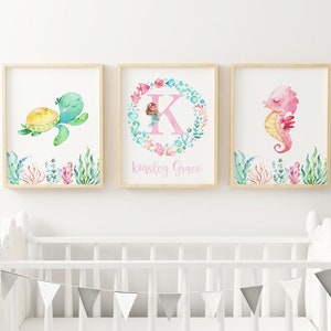 May include: Three watercolor prints featuring a sea turtle, a mermaid with the letter K, and a seahorse. The prints are framed in natural wood and have a white background. The mermaid print also includes the text "Kingsley Grace".