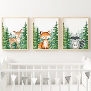 May include: Three framed watercolor prints featuring woodland animals. The prints depict a deer, a fox, and a raccoon standing in a forest setting. Each print has a white background and green trees.