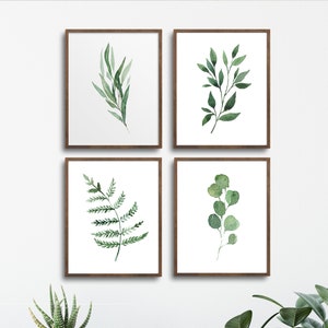 May include: Four framed watercolor prints of green leaves and branches on a white background. The prints are arranged in a grid pattern on a white wall.
