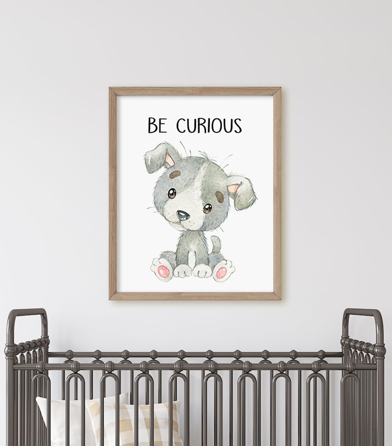 May include: A framed print with a watercolor illustration of a gray and white puppy sitting with the text "BE CURIOUS" above it. The print is hanging on a white wall above a gray crib.