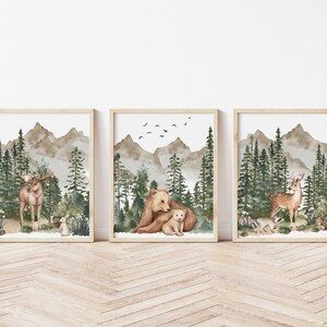 K&ouml;nnte beinhalten: Drei Aquarelle mit einem Elch, einem B&auml;ren und einem Reh in einer Waldlandschaft. Die Bilder sind in Holz gerahmt und haben einen wei&szlig;en Hintergrund.