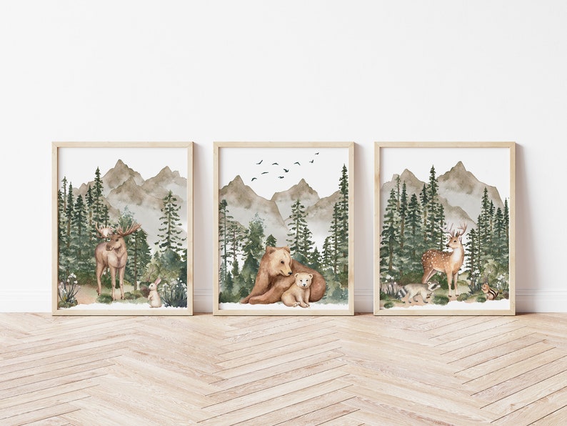 K&ouml;nnte beinhalten: Drei Aquarelle mit einem Elch, einem B&auml;ren und einem Reh in einer Waldlandschaft. Die Bilder sind in Holz gerahmt und haben einen wei&szlig;en Hintergrund.