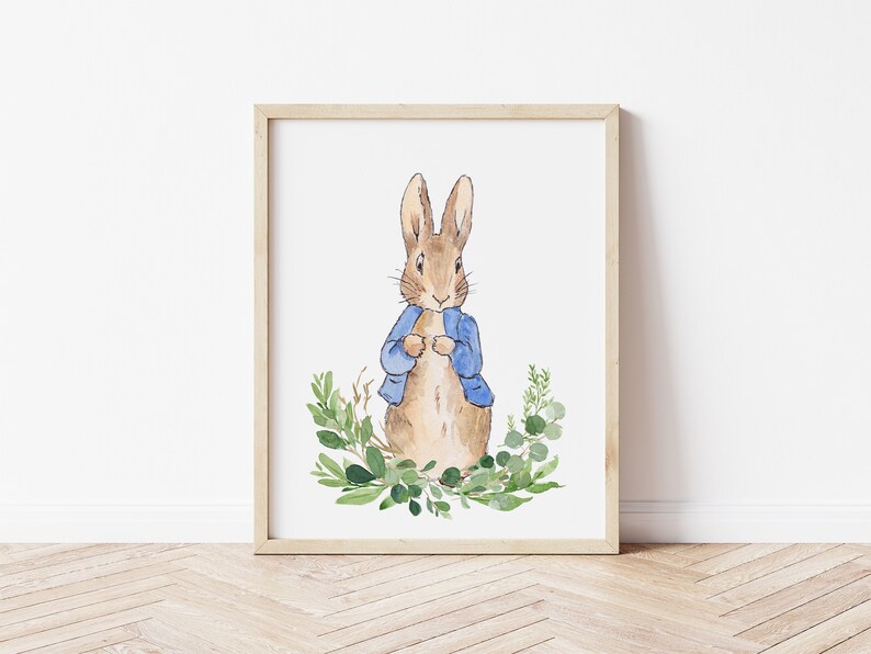 May include: A watercolor illustration of Peter Rabbit wearing a blue jacket, standing in a wreath of green leaves.