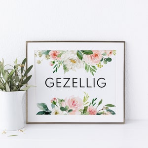 May include: A framed print with a white background and a floral design in shades of pink and green. The text "GEZELLIG" is printed in black in the center of the print.