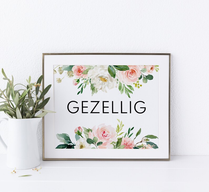 May include: A framed print with a white background and a floral design in shades of pink and green. The text "GEZELLIG" is printed in black in the center of the print.