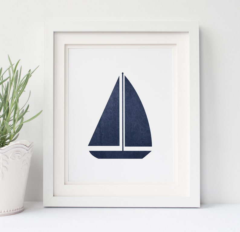 May include: A framed print of a navy blue sailboat silhouette on a white background.