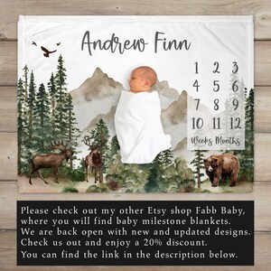 K&ouml;nnte beinhalten: Eine wei&szlig;e Babydecke mit einer Aquarell-Waldszene, Bergen und einem kleinen B&auml;ren. Die Decke ist mit dem Namen "Andrew Finn" personalisiert und enth&auml;lt eine Zahlentabelle, um das Wachstum des Babys in Wochen und Monaten zu verfolgen.