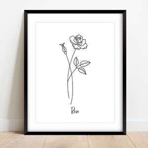 May include: A black and white line drawing of a rose with a bud and leaves. The drawing is framed in a black frame and the word "Rose" is written below the drawing.