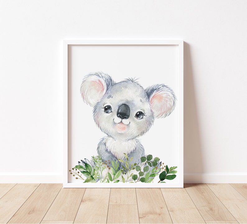 Puede incluir: Una ilustraci&oacute;n de acuarela de un lindo koala con ojos grandes y una dulce sonrisa. El koala est&aacute; rodeado de hojas verdes y flores.
