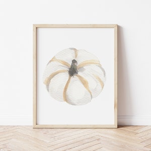 May include: A watercolor painting of a white pumpkin with brown stem and gold accents. The pumpkin is framed in a light wood frame.