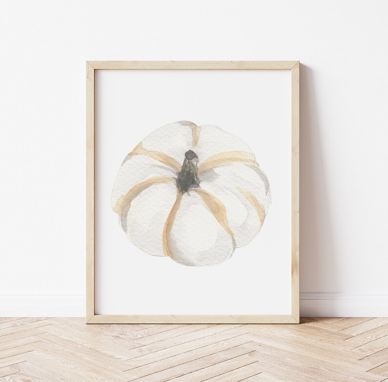 May include: A watercolor painting of a white pumpkin with brown stem and gold accents. The pumpkin is framed in a light wood frame.