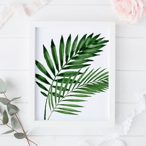 K&ouml;nnte beinhalten: Ein wei&szlig;er Rahmen mit einem Aquarellbild von gr&uuml;nen Palmbl&auml;ttern auf wei&szlig;em Hintergrund.